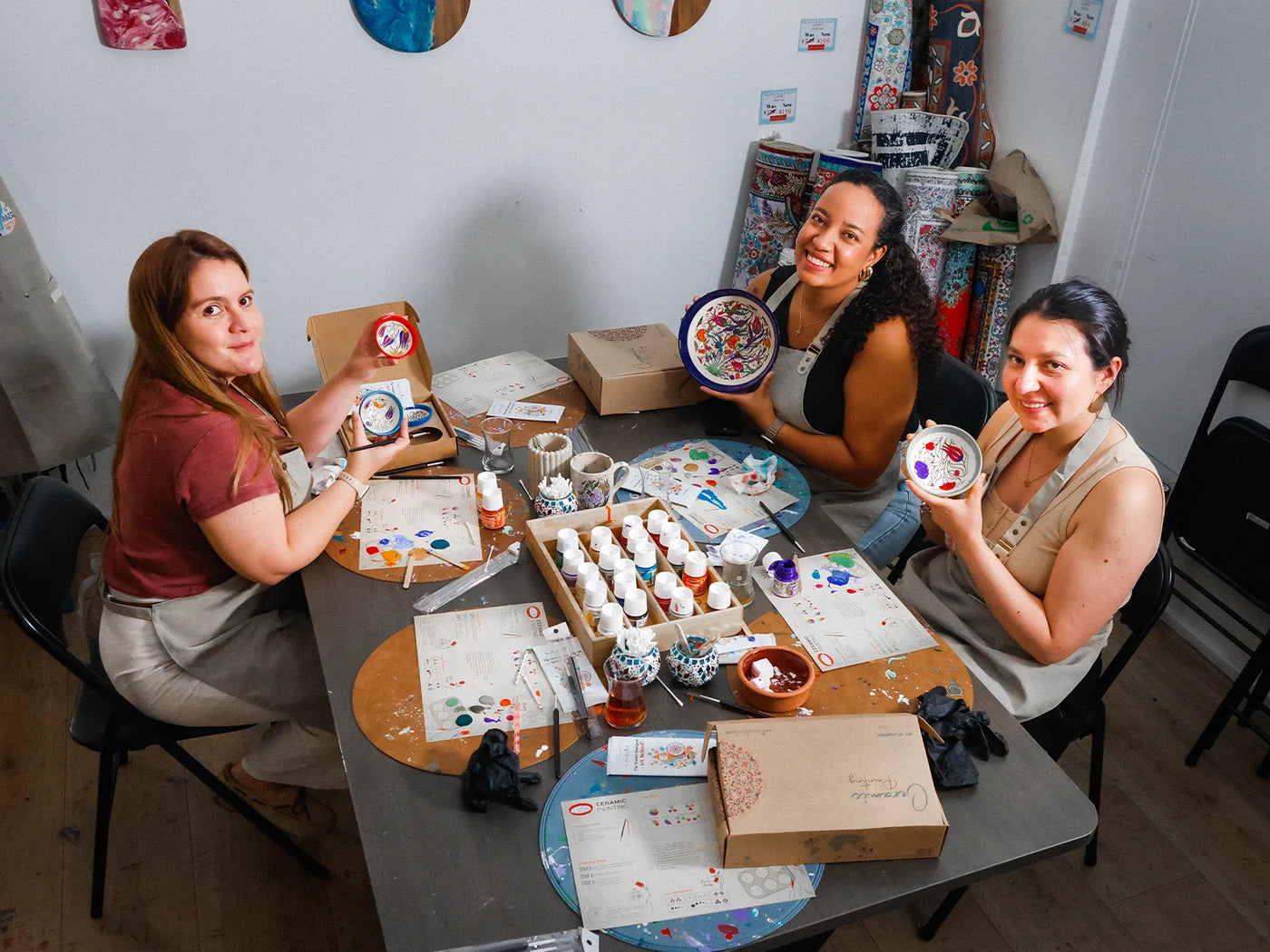 Friends sharing their finished ceramic pieces around a workshop table