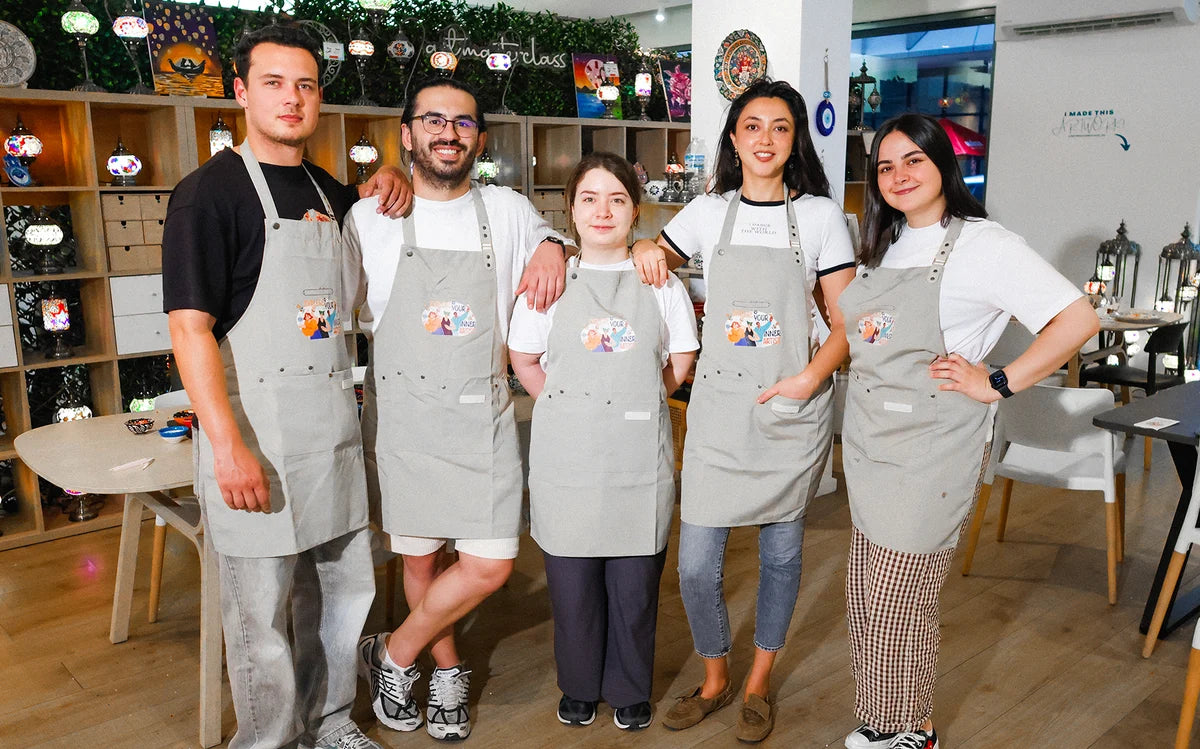 A group of workshop guests wearing aprons in the Art Masterclass studio