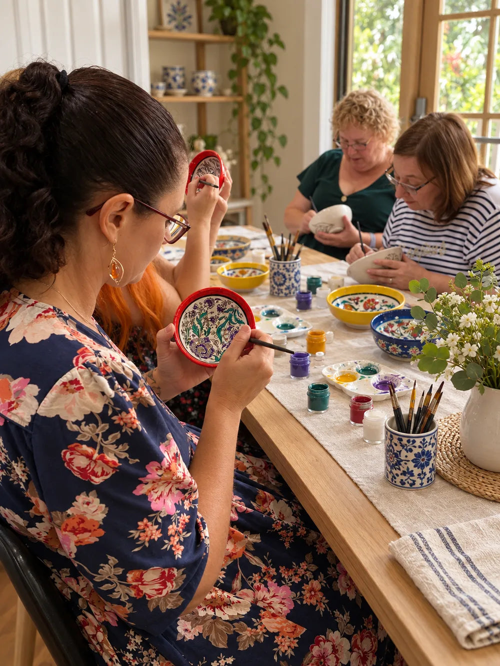 Guests painting ceramics around a studio table