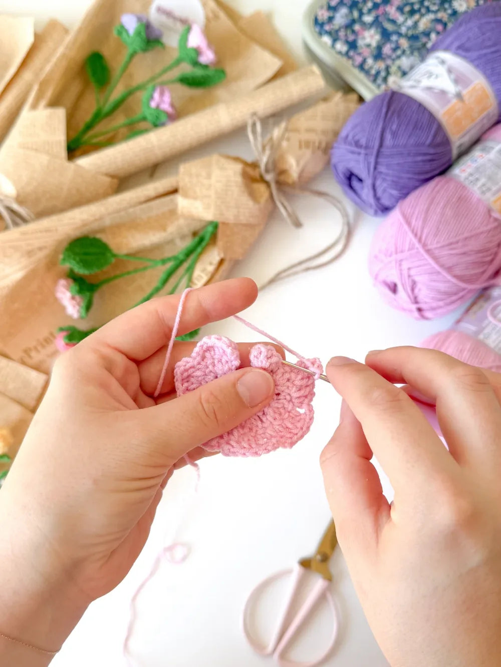 A crochet rose in progress beside coloured yarn